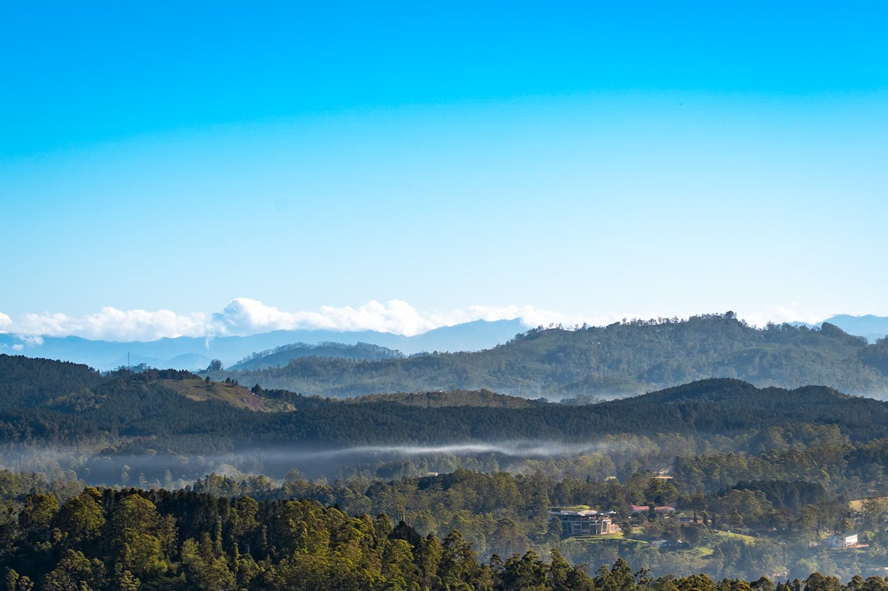 Breathtaking view of misty mountains and forests in Sri Lanka, under a clear blue sky.